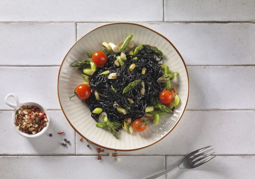 Espaguetis de merluza con tinta de sepia con ajetes, trigueros y tomate cherry